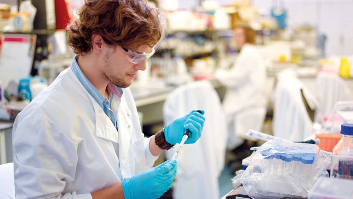 male scientist working in lab with gloves on